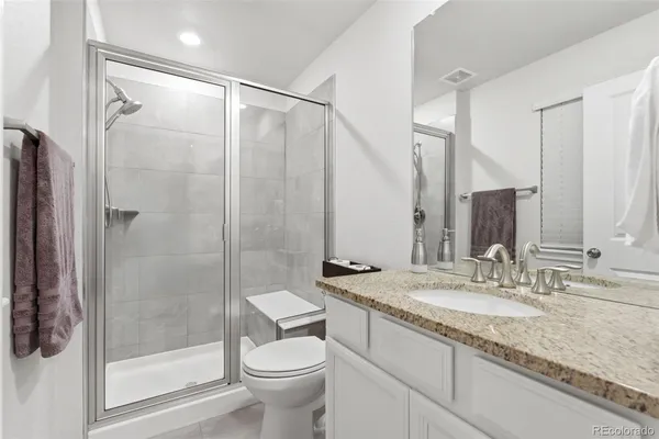 a bathroom with a granite countertop sink toilet and shower