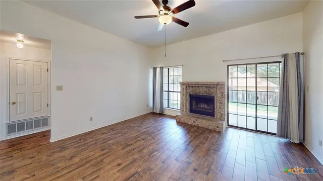 an empty room with wooden floor fireplace and windows