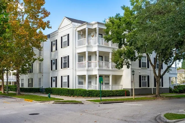 a front view of a building with garden and trees