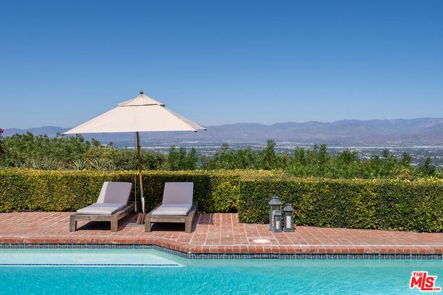 a view of a house with pool fire pit a table and chairs in a patio