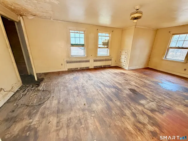 an empty room with wooden floor and windows