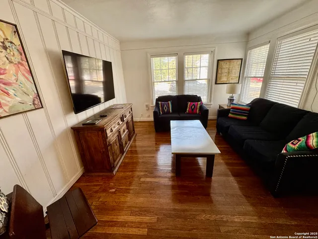 a living room with furniture a flat screen tv and wooden floor