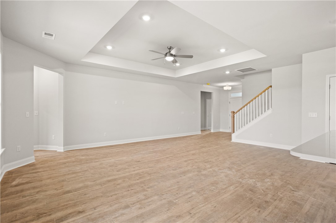 554 Hydrangea Street, Unit LOT 67 Seneca, SC 29678 - Photo 5 of 26 A spacious living area with warm flooring and a refined tray ceiling featuring recessed lighting.
