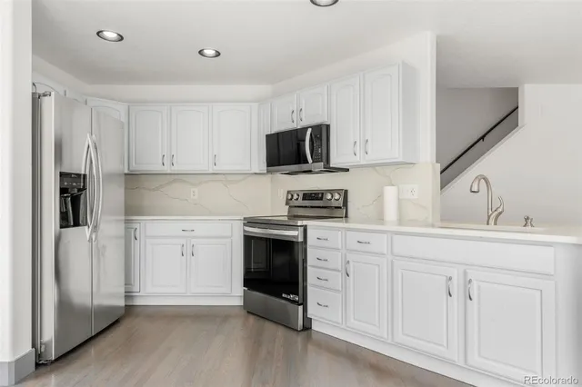 a kitchen with white cabinets and stainless steel appliances