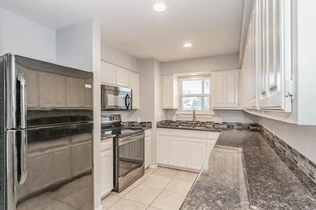 a kitchen with granite countertop a refrigerator stove and cabinets