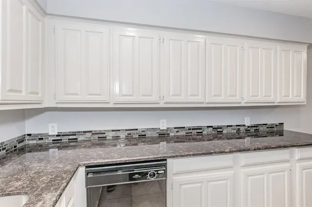 a kitchen with granite countertop white cabinets and a sink