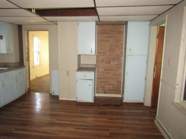 a view of a hallway with wooden floor and a bathroom