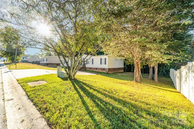 a view of swimming pool with large trees and wooden fence