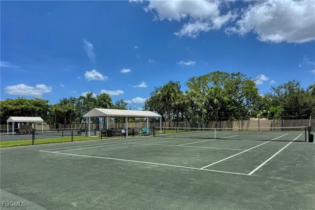 a view of a tennis ground with large trees