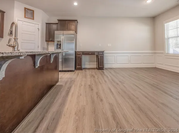 a kitchen with stainless steel appliances granite countertop a stove a sink dishwasher and a refrigerator with wooden floor