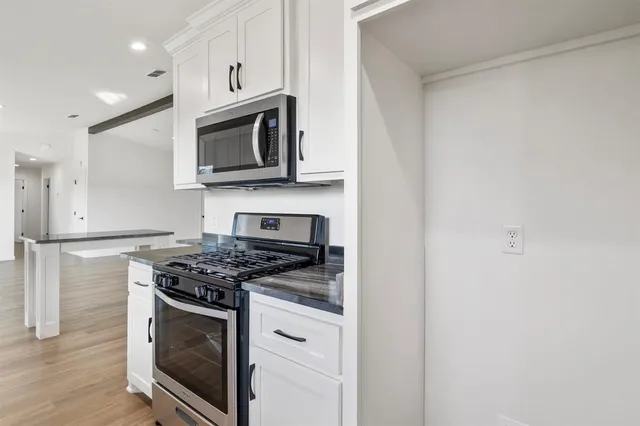 a kitchen with stainless steel appliances granite countertop a stove a microwave and a refrigerator