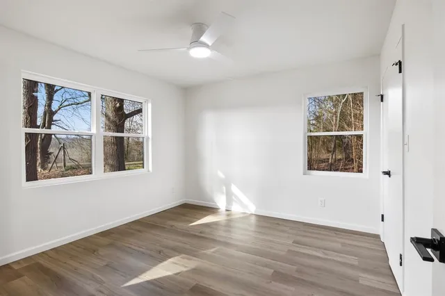 a view of an empty room with a window and wooden floor