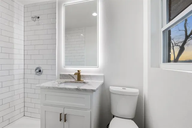 a bathroom with a granite countertop toilet sink and mirror