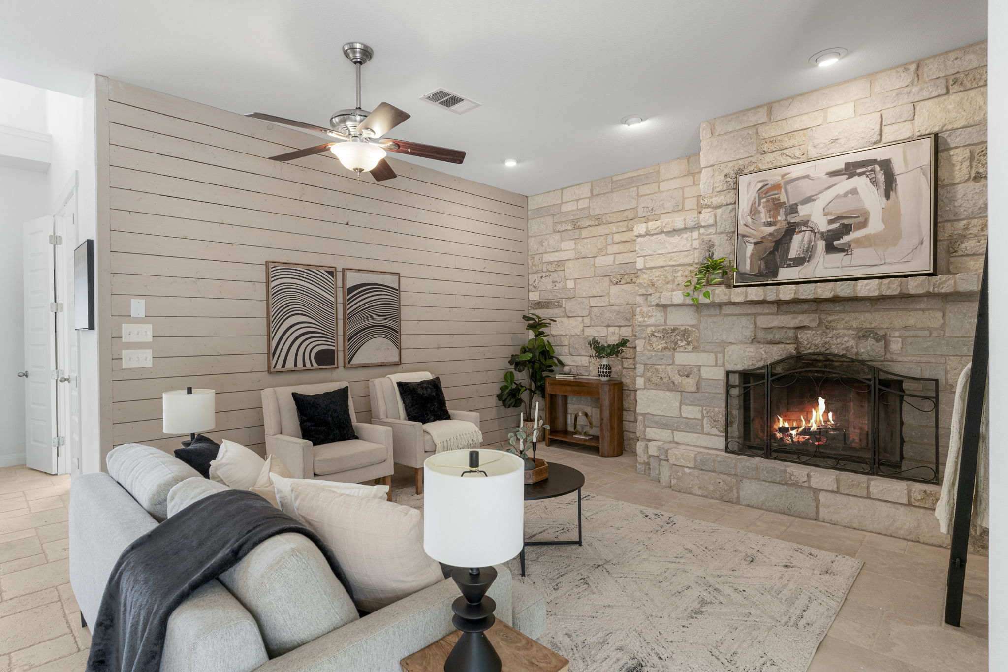 1129 Cedar Pass Road Driftwood, TX 78619 - Photo 5 of 40 Imagine relaxing in this living area! You’ve got the floor-to-ceiling stone fireplace on one side and a beautiful horizontal shiplap accent wall on the other. It’s the perfect spot to cozy up by the fire.