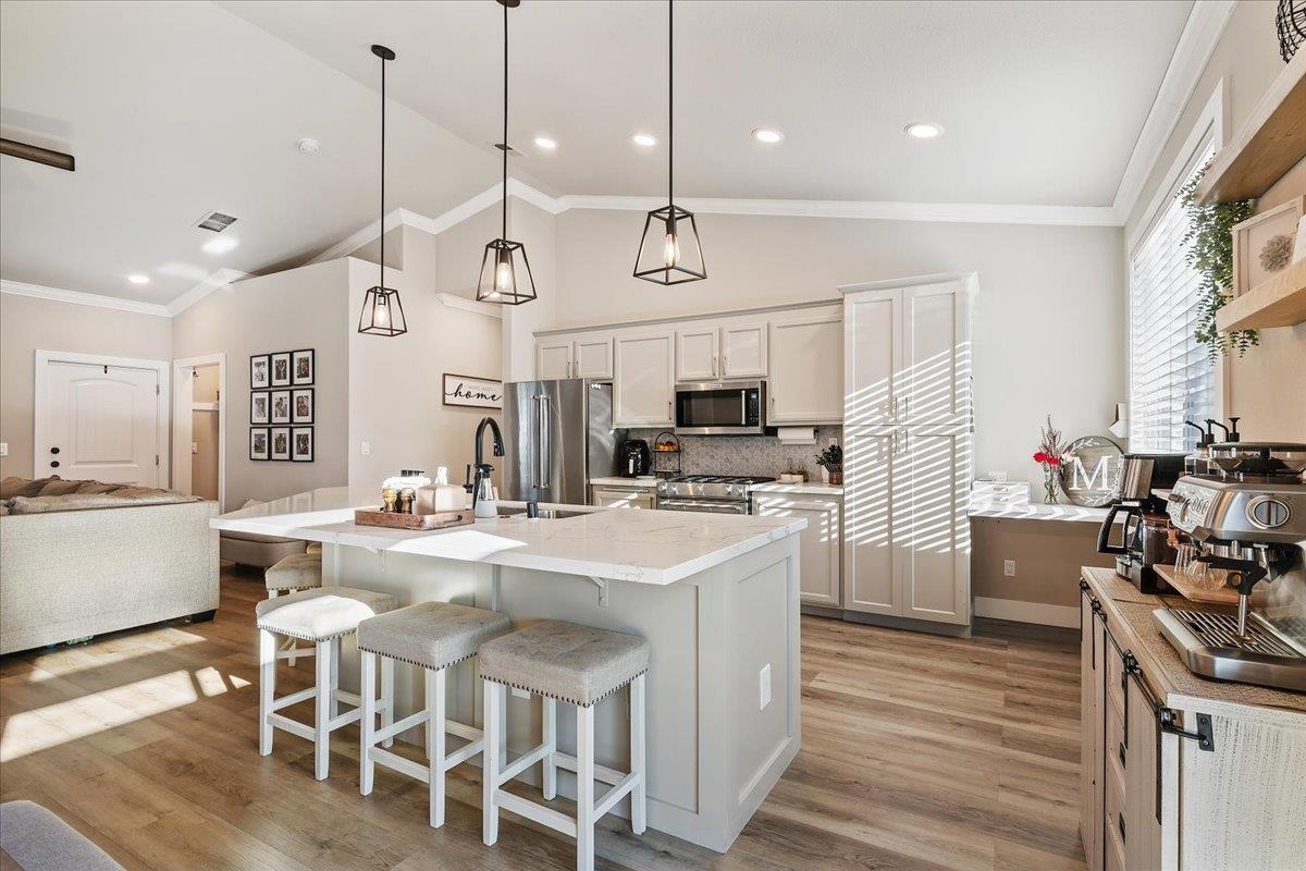 1105 Deerpark Road Oakley, CA 94561 - Photo 10 of 25 Kitchen with a breakfast bar area, crown molding, a kitchen island with sink, pendant lighting, and lofted ceiling