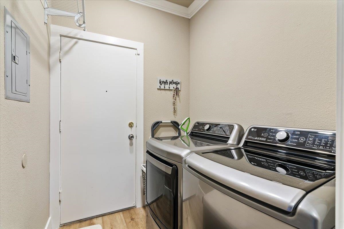1105 Deerpark Road Oakley, CA 94561 - Photo 21 of 25 Washroom featuring electric panel, light wood-style floors, washing machine and dryer, crown molding, and a textured wall