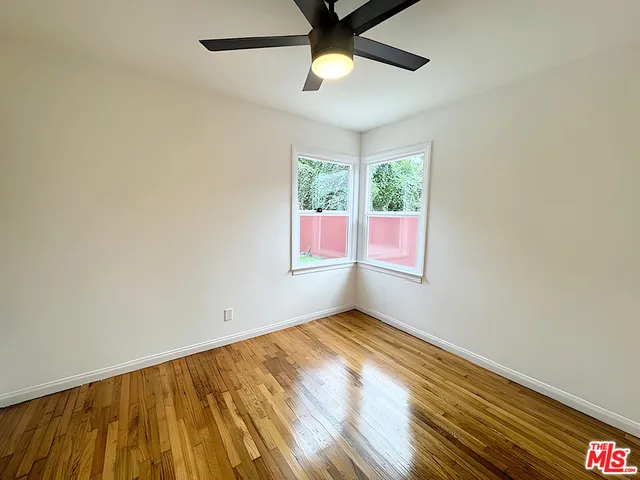 a view of empty room with wooden floor and fan