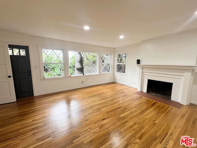 a view of empty room with wooden floor and fireplace