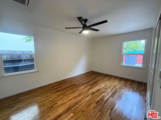 a view of empty room with wooden floor and fan