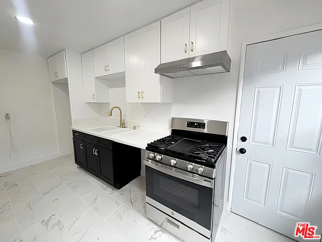 a kitchen with stainless steel appliances a stove and white cabinets
