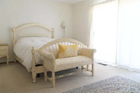 a white bed sitting in a room next to a window