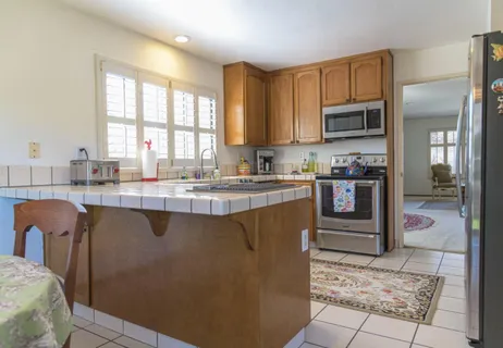 a kitchen with stainless steel appliances granite countertop a refrigerator a sink a stove top oven and a counter space