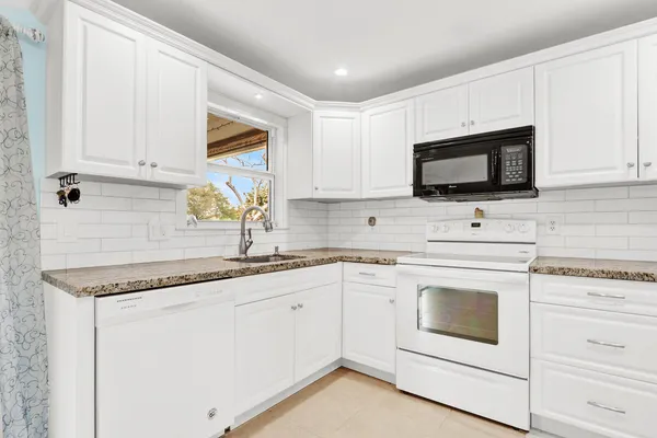 a kitchen with granite countertop white cabinets sink and white appliances