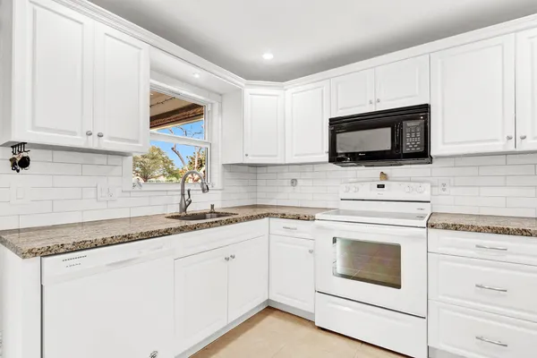 a kitchen with white cabinets appliances and a sink