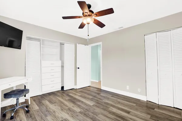 a view of a livingroom with a ceiling fan & wooden floor