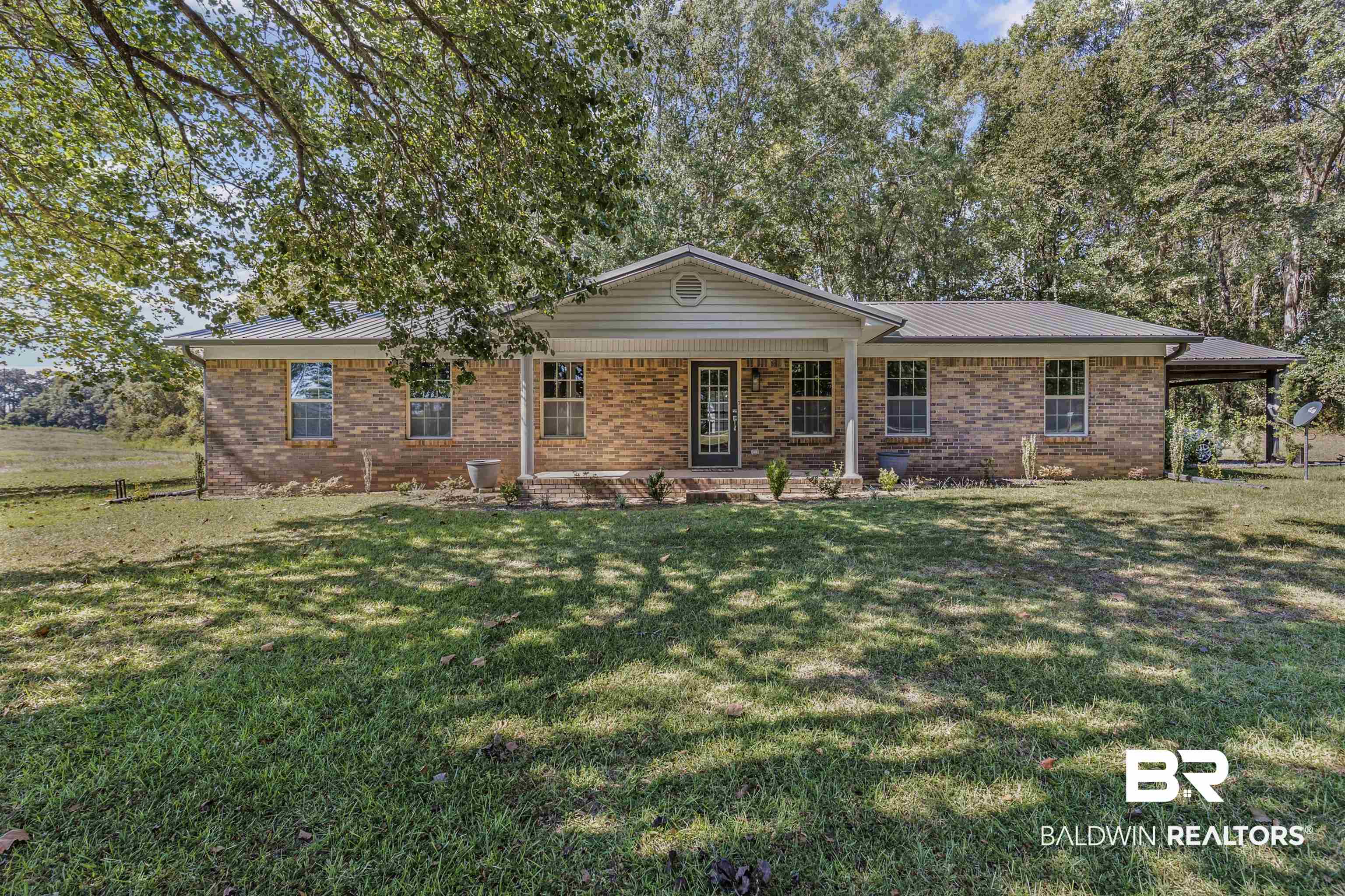 8911 Owassa Road Evergreen, AL 36401 - Photo 2 of 24 Ranch-style home with covered porch, brick siding, and a front lawn