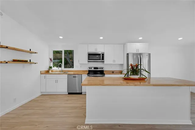 a kitchen with stainless steel appliances granite countertop a refrigerator a stove top oven a sink dishwasher and wooden floor