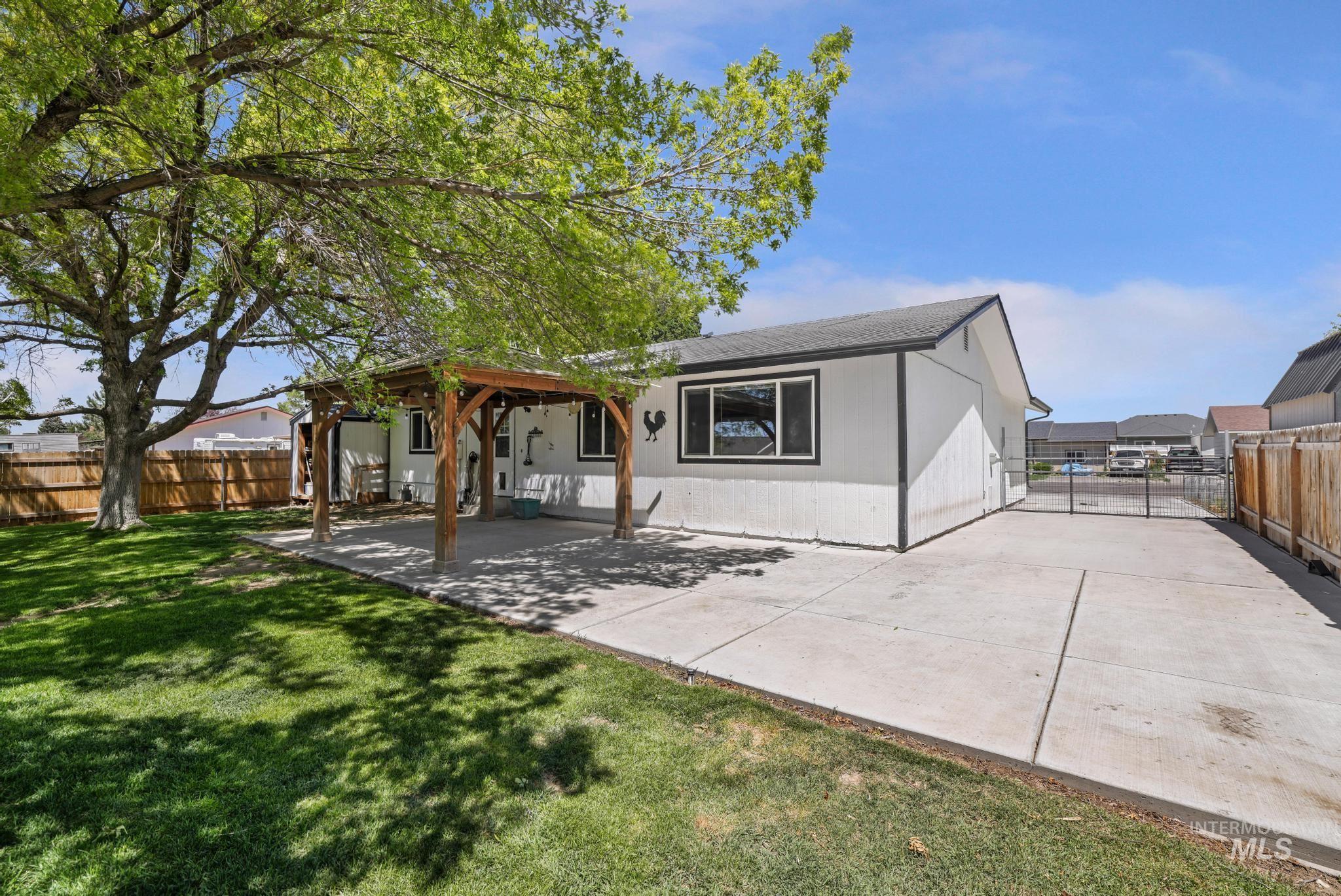 712 Locust Street Kimberly, ID 83341 - Photo 4 of 26 Expansive concrete patio featuring a wooden gazebo with a metal roof, mature shade trees, and a manicured lawn