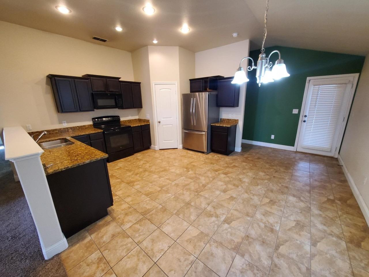 5602 111th Street Lubbock, TX 79424 - Photo 3 of 13 a kitchen with stainless steel appliances kitchen island granite countertop furniture a refrigerator a sink a stove top oven and a refrigerator