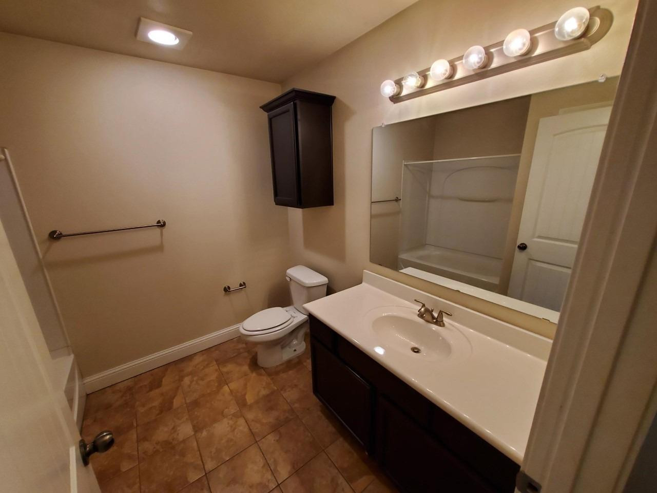5602 111th Street Lubbock, TX 79424 - Photo 6 of 13 a bathroom with a sink a toilet and mirror