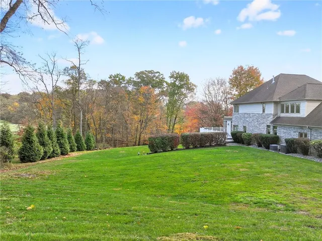 a view of a yard in front of a house with plants and large tree