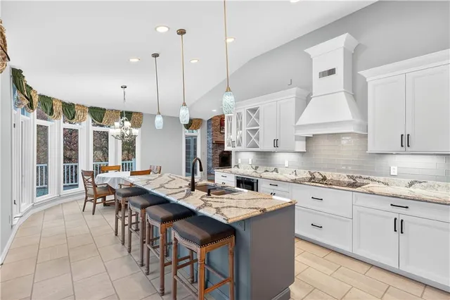 a open kitchen with stainless steel appliances granite countertop a stove a sink a oven a dining table and chairs