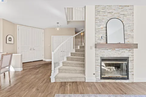 a large white kitchen with stainless steel appliances granite countertop a stove a sink a refrigerator and white cabinets with wooden floor
