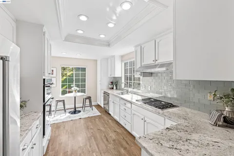 a kitchen with granite countertop a sink stainless steel appliances and cabinets