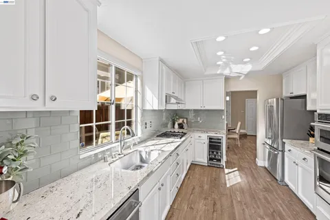 a kitchen with stainless steel appliances granite countertop a stove a sink dishwasher and cabinets with wooden floor