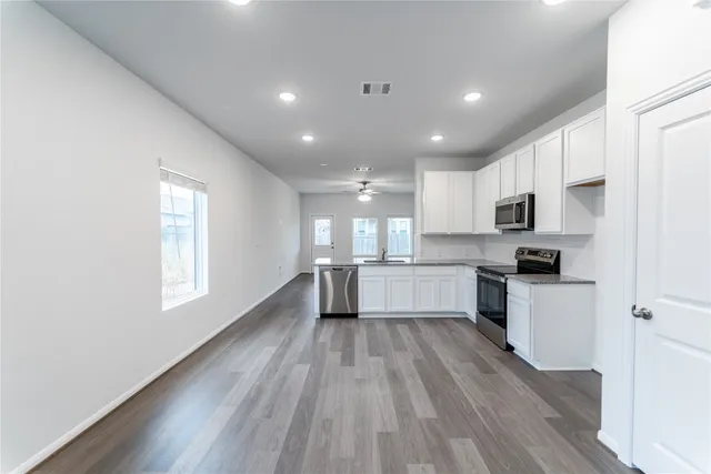 a kitchen with white cabinets and wooden floor