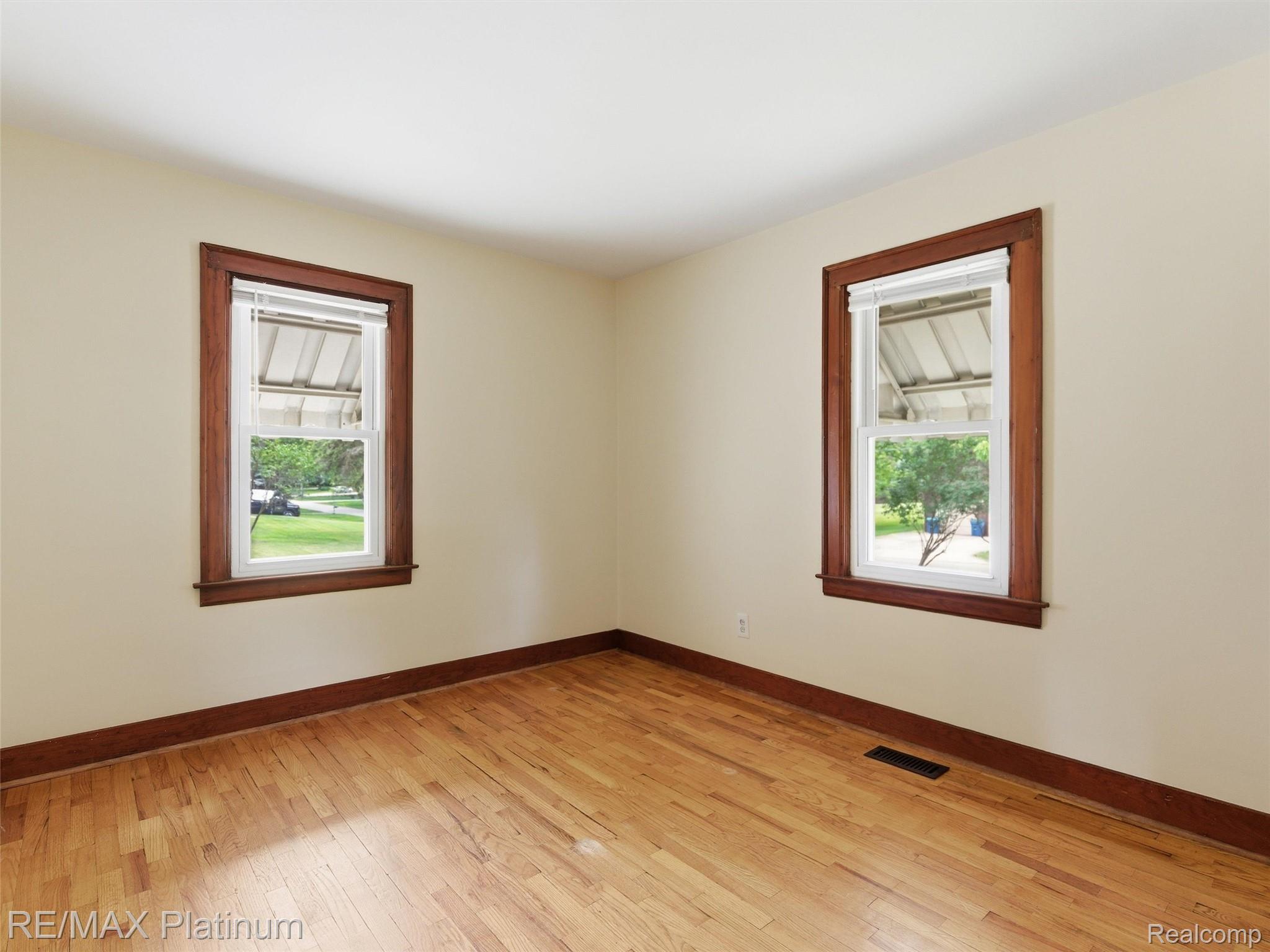 6335 Silver Lake Road Linden, MI 48451 - Photo 20 of 61 Room featuring wood-finish flooring, two windows with wood trim, and light-toned walls