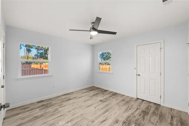 a view of empty room with wooden floor and ceiling fan