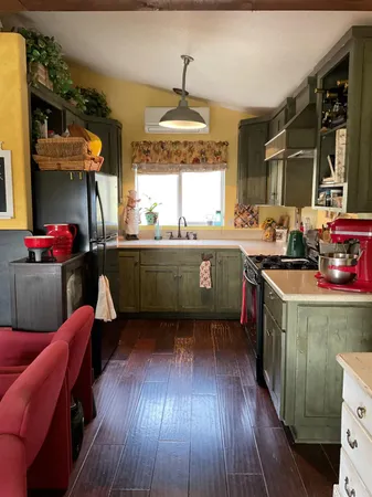 a kitchen with wooden floors and a view of living room
