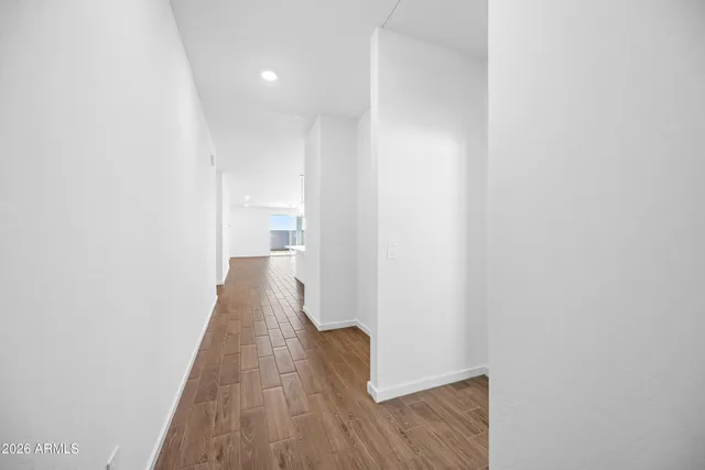 a view of a hallway with wooden floor and a bathroom