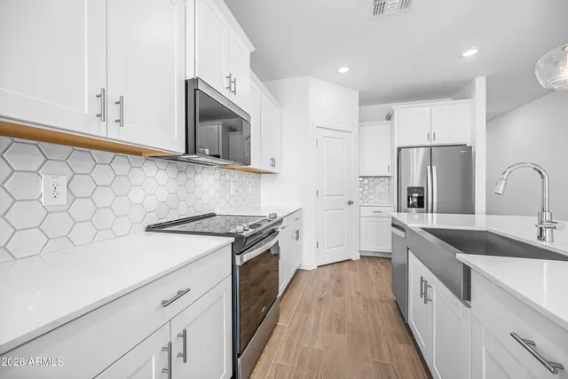 a kitchen with stainless steel appliances granite countertop white cabinets a sink a stove a refrigerator and white cabinets