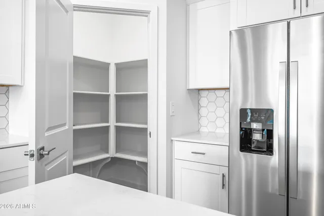 a kitchen with a refrigerator and white cabinets