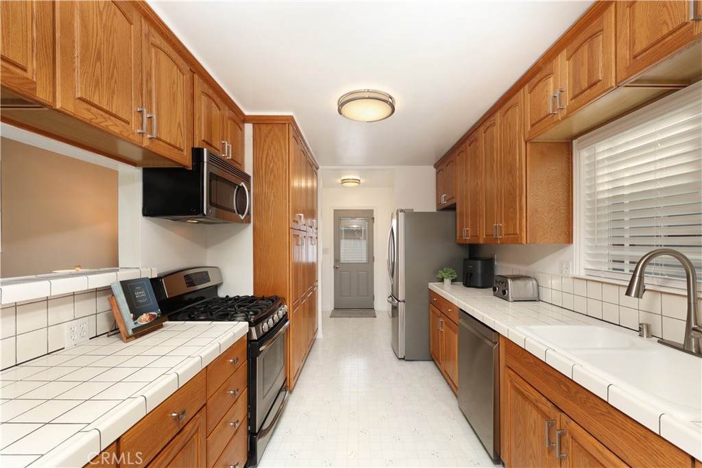 6116 Arbor Road Lakewood, CA 90713 - Photo 11 of 46 a kitchen with stainless steel appliances kitchen island granite countertop a sink stove and cabinets