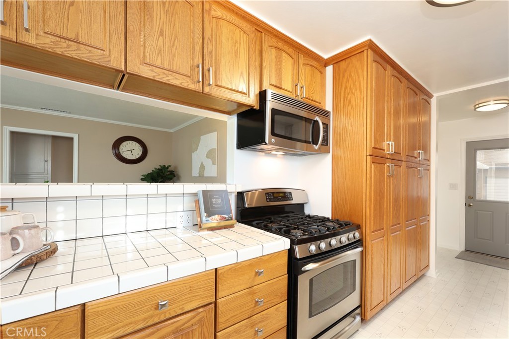 6116 Arbor Road Lakewood, CA 90713 - Photo 13 of 46 a kitchen with stainless steel appliances granite countertop a stove a microwave and a refrigerator