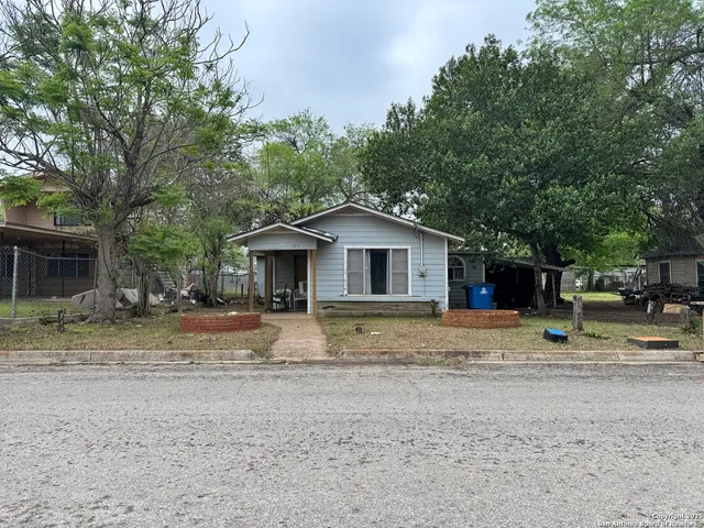 a view of a house with a yard and large tree