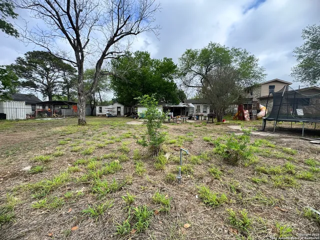 a tall yellow house with trees in the background